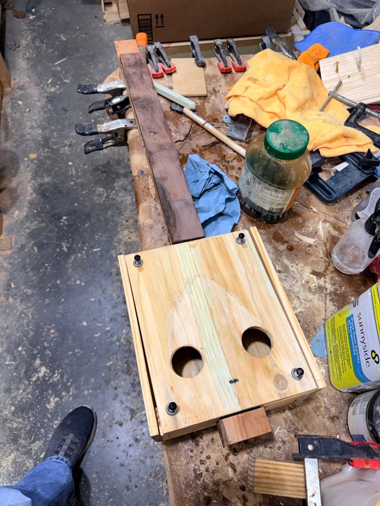 A Cigar Box Guitar on a cluttered work table.
